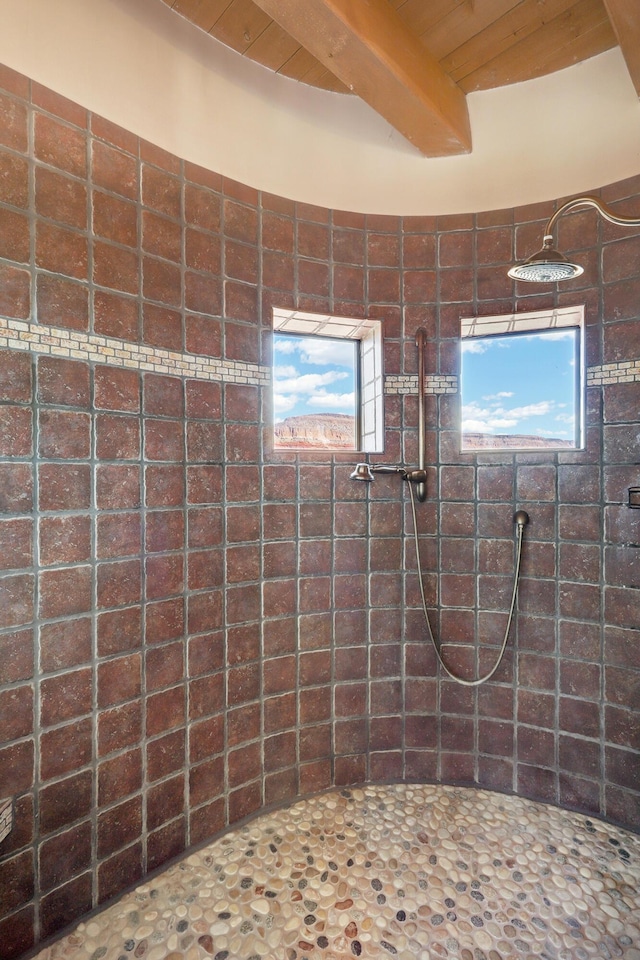 bathroom with beamed ceiling and tiled shower