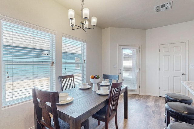 dining space featuring wood-type flooring and a notable chandelier