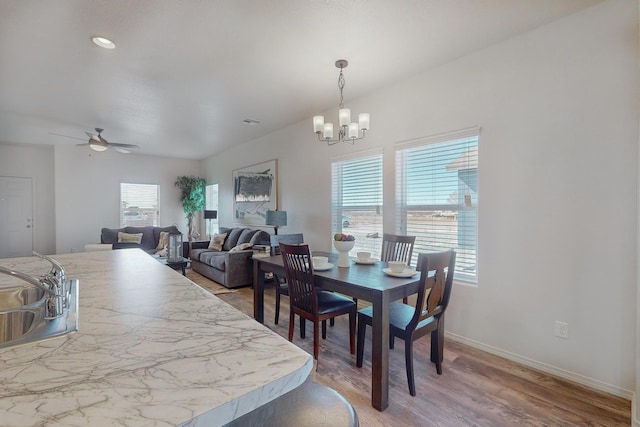 dining area with sink, a healthy amount of sunlight, ceiling fan with notable chandelier, and hardwood / wood-style floors