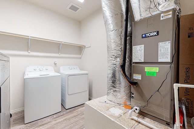laundry room with light hardwood / wood-style flooring, independent washer and dryer, and heating utilities