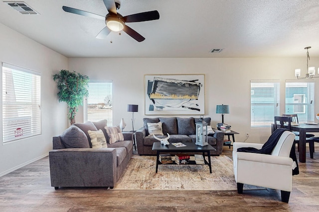 living room with ceiling fan with notable chandelier and hardwood / wood-style flooring