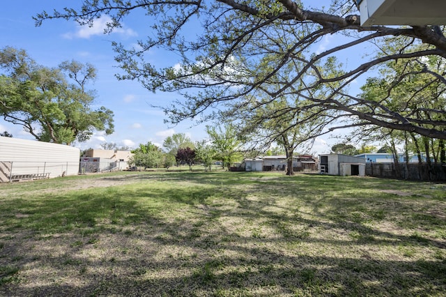 view of yard with fence, a storage unit, and an outdoor structure