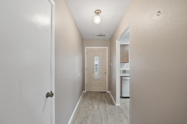 entryway with a textured wall, light wood-type flooring, visible vents, and baseboards