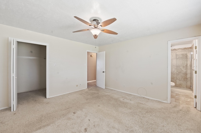 unfurnished bedroom featuring baseboards, connected bathroom, ceiling fan, carpet flooring, and a closet