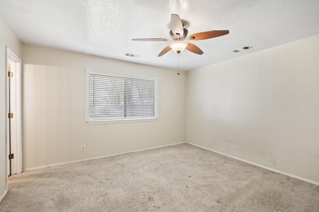 carpeted spare room featuring a ceiling fan, visible vents, and a textured ceiling