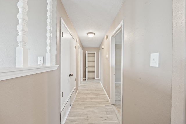 corridor with light wood-type flooring and baseboards