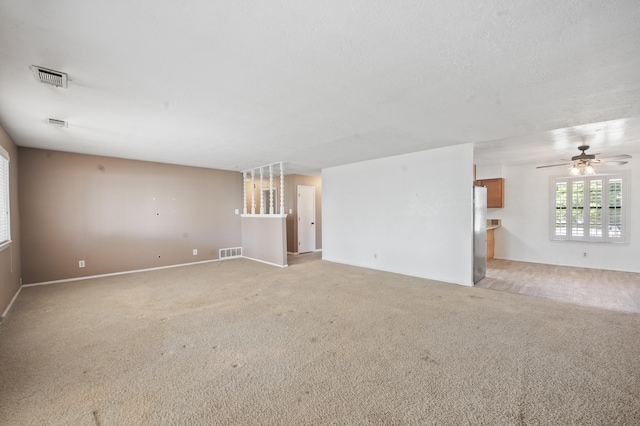 unfurnished room featuring a ceiling fan, light colored carpet, visible vents, and a textured ceiling