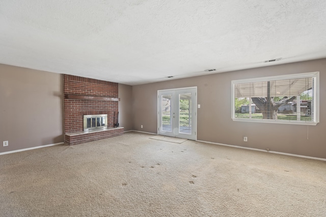 unfurnished living room with a brick fireplace, carpet, visible vents, and a textured ceiling