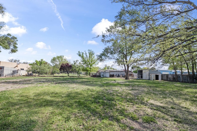 view of yard featuring a storage shed, fence, and an outdoor structure