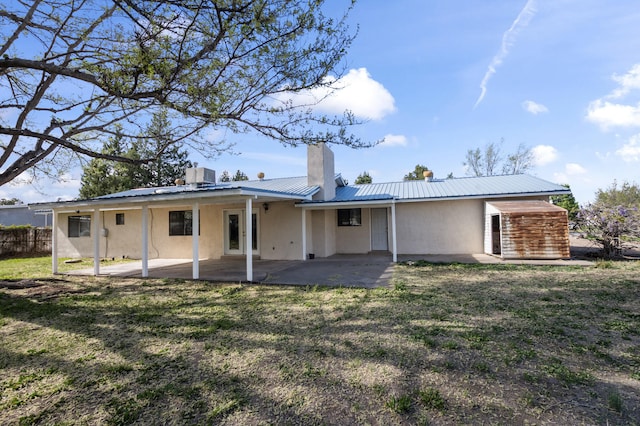 rear view of property with stucco siding, metal roof, cooling unit, and a patio