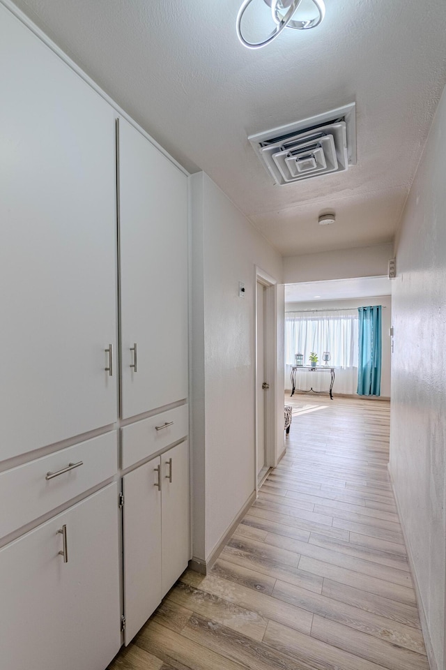 corridor featuring light hardwood / wood-style flooring and a textured ceiling