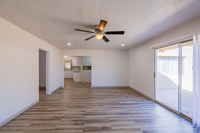 unfurnished living room featuring ceiling fan, light hardwood / wood-style floors, and a textured ceiling