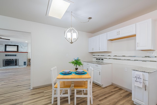 kitchen with pendant lighting, white cabinetry, tasteful backsplash, and light hardwood / wood-style floors