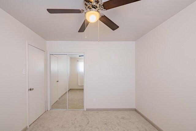 unfurnished bedroom featuring light colored carpet, ceiling fan, and a closet