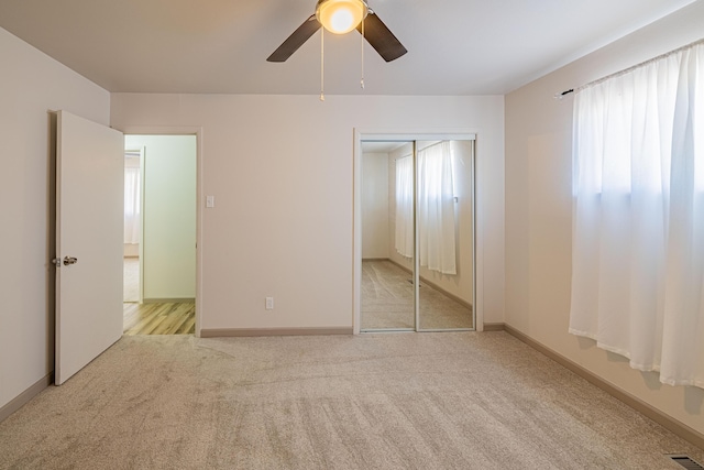 unfurnished bedroom with light colored carpet, a closet, and ceiling fan