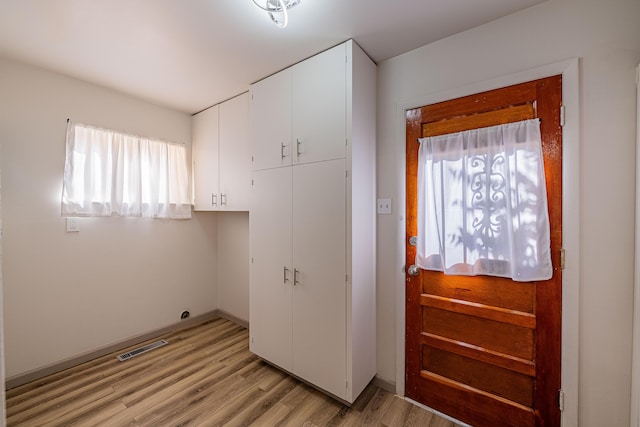 clothes washing area with light hardwood / wood-style flooring