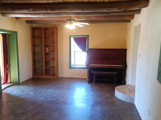 unfurnished living room with ceiling fan, dark tile flooring, and beamed ceiling