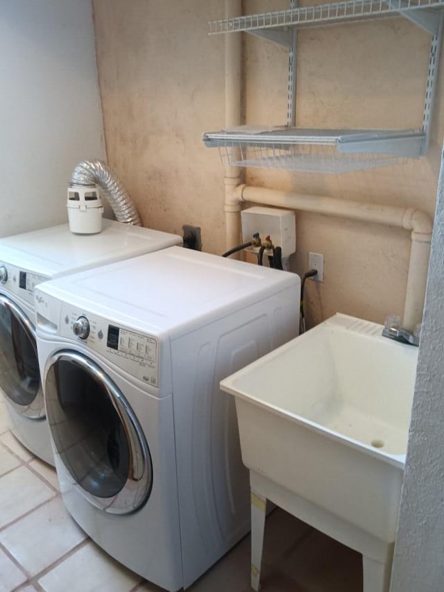 washroom featuring sink, hookup for a washing machine, washing machine and dryer, and light tile flooring