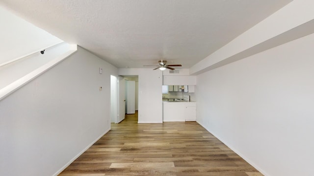 unfurnished living room featuring a textured ceiling, ceiling fan, and wood-type flooring