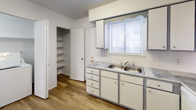 kitchen featuring sink, light hardwood / wood-style flooring, dishwasher, washer / dryer, and white cabinets