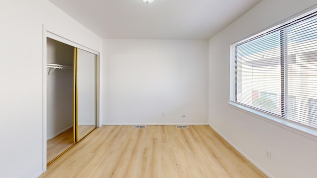 unfurnished bedroom with a closet and light wood-type flooring