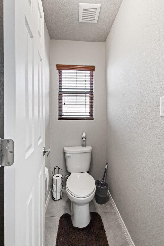 bathroom featuring a textured ceiling, toilet, and tile flooring