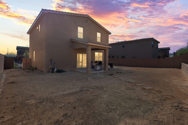 back house at dusk featuring a patio