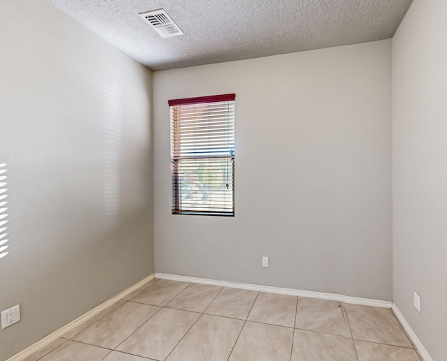 unfurnished room featuring a textured ceiling and light tile flooring