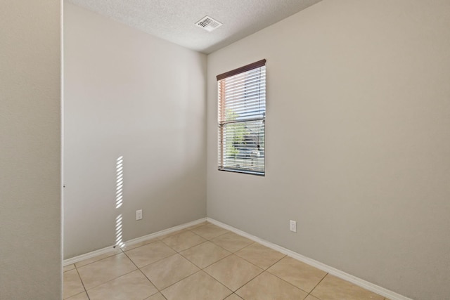 tiled empty room featuring a textured ceiling