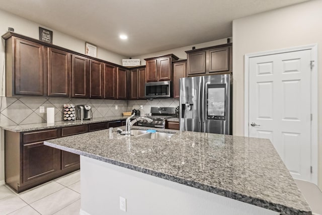 kitchen featuring dark brown cabinets, appliances with stainless steel finishes, backsplash, light tile flooring, and sink