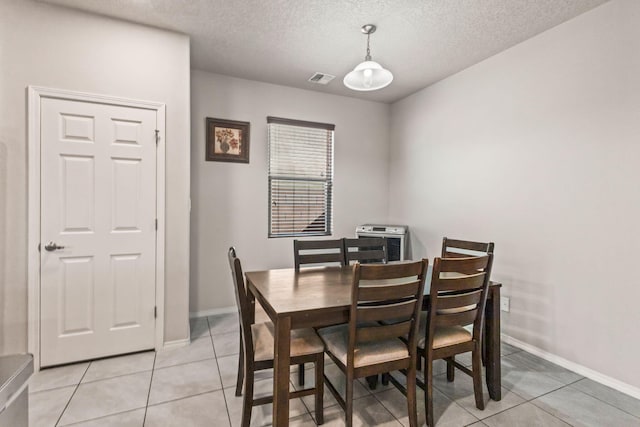 dining space with a textured ceiling and light tile flooring