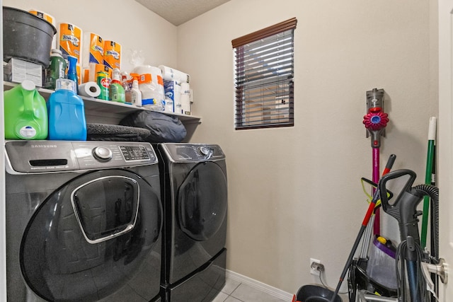 clothes washing area with tile floors and separate washer and dryer