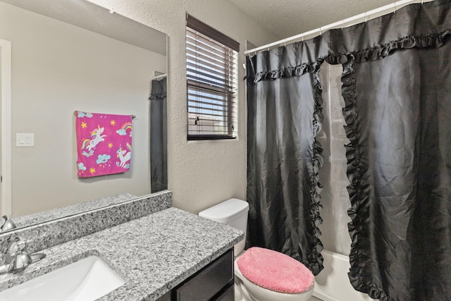 bathroom with a textured ceiling, oversized vanity, and toilet