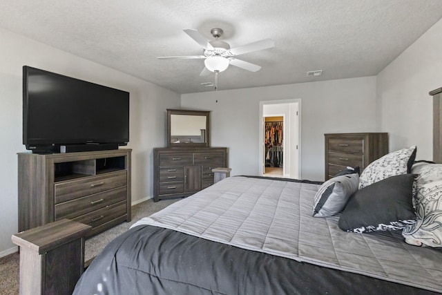 bedroom with a closet, ceiling fan, a spacious closet, and carpet floors