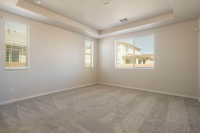 carpeted empty room featuring baseboards, visible vents, and a raised ceiling