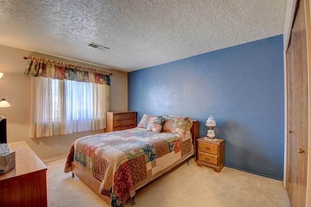 bedroom featuring light carpet and a textured ceiling