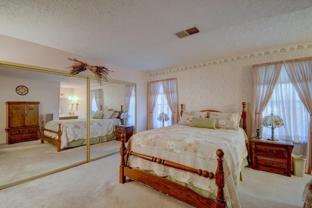 bedroom featuring light carpet, a closet, and a textured ceiling