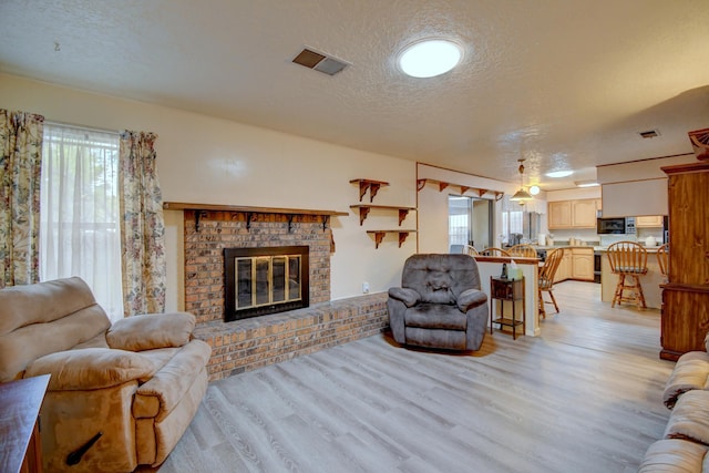 living room with a fireplace, light hardwood / wood-style flooring, and a textured ceiling