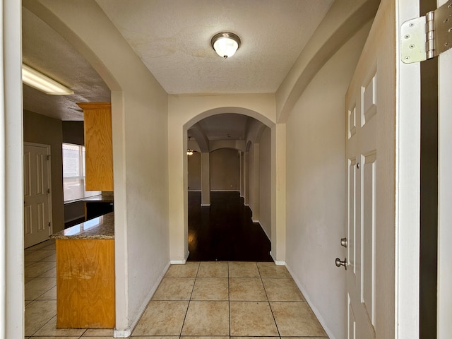 corridor featuring a textured ceiling and light tile floors