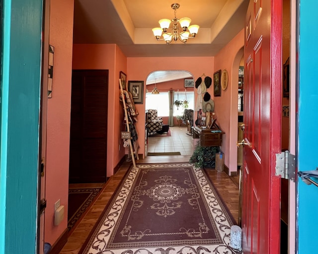 foyer entrance with dark hardwood / wood-style floors, a tray ceiling, and a chandelier