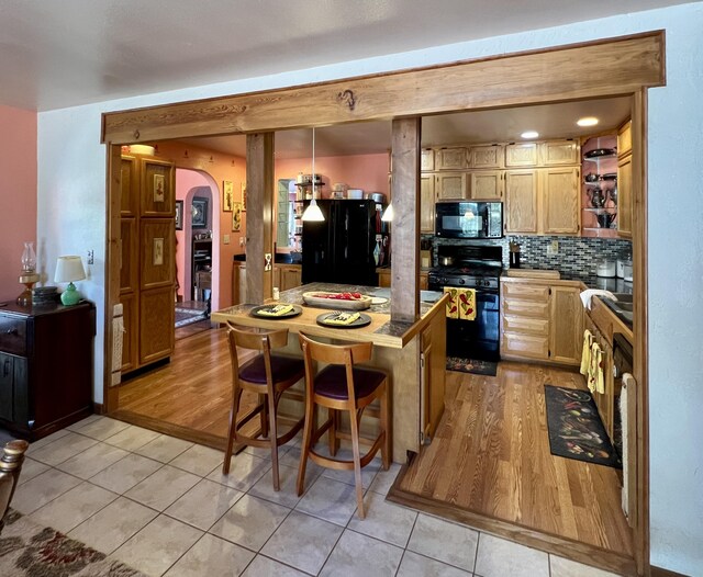 787 Timberlake Rd, Ramah, NM 87321 - kitchen with black appliances, arched walkways, light tile patterned floors, backsplash, and a center island