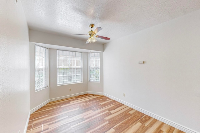 empty room featuring ceiling fan, light hardwood / wood-style floors, and a textured ceiling