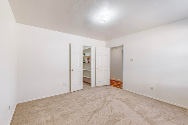 unfurnished bedroom featuring light carpet and a spacious closet