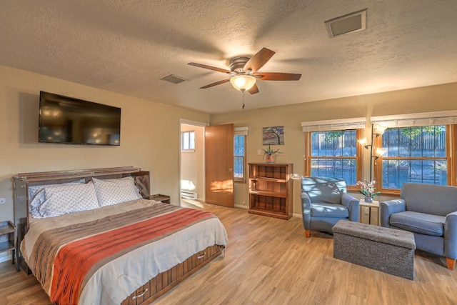 bedroom featuring a baseboard radiator, hardwood / wood-style floors, a textured ceiling, and ceiling fan