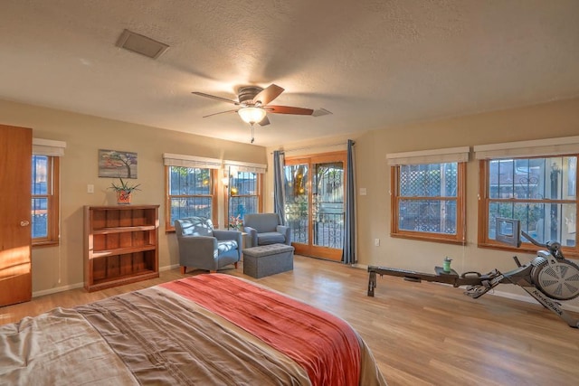 bedroom with light hardwood / wood-style flooring, a textured ceiling, access to outside, and ceiling fan