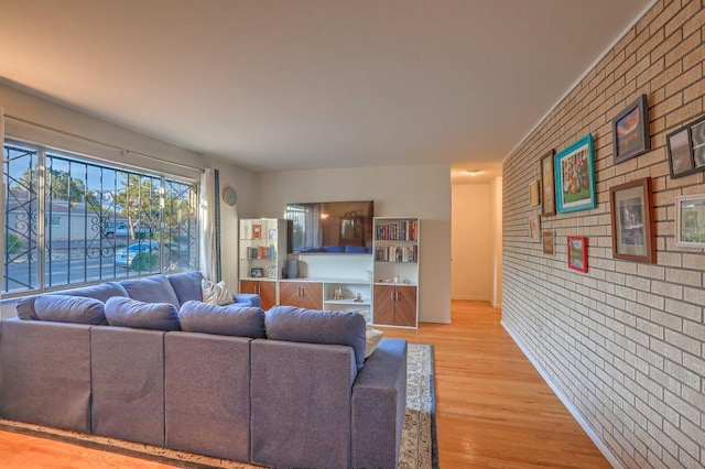 living room featuring brick wall and light hardwood / wood-style floors