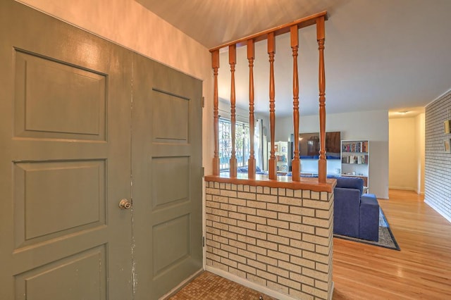 entryway with brick wall and light wood-type flooring