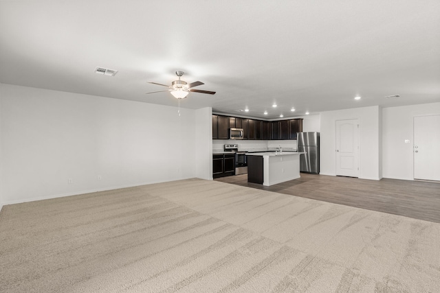 unfurnished living room featuring ceiling fan and light carpet