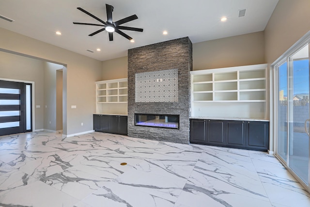 unfurnished living room with a fireplace, built in shelves, and ceiling fan