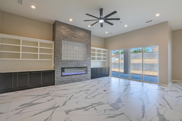 unfurnished living room with a fireplace, built in shelves, and ceiling fan